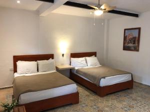 a bedroom with two beds and a ceiling fan at Hotel Casa Bamboo in Valladolid