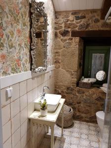 uma casa de banho em pedra com um lavatório e um espelho em La Calleja em Arzúa
