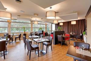 a restaurant with tables and chairs and windows at Logis Beaujoire Hôtel in Nantes