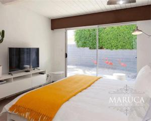 a bedroom with a bed and a tv and a window at Villa Finola in Palm Springs