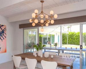 a dining room with a wooden table and white chairs at Villa Finola in Palm Springs
