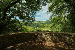 a stone wall with trees and a road in the background at La Loggetta - Chianti apartments in Gaiole in Chianti