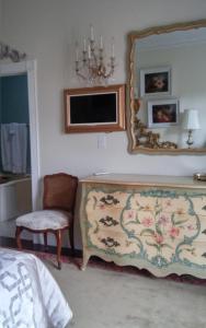 um quarto com uma cama, um espelho e uma cadeira em Inntiquity, A Country Inn em Logansport