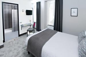 ein Hotelzimmer mit einem großen Bett und einem Schreibtisch in der Unterkunft Logis Hotel Restaurant Nougier in Saint-Étienne-de-Fursac