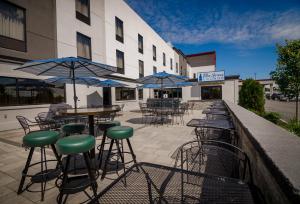 an outdoor patio with tables and chairs and umbrellas at Holiday Inn & Suites Syracuse Airport - Liverpool by IHG in Liverpool