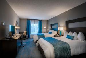 a hotel room with two beds and a desk at Holiday Inn & Suites Syracuse Airport - Liverpool, an IHG Hotel in Liverpool