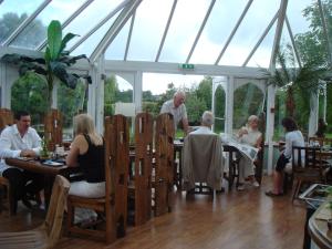 The House near Bath في Woolverton: مجموعة من الناس يجلسون على الطاولات في البيت الزجاجي