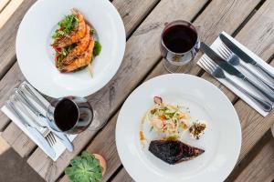 two plates of food and a glass of wine on a wooden table at The Red Lion, Barn Accommodation in Thornby