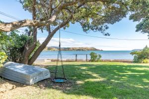 Eine Schaukel hängt von einem Baum neben dem Wasser in der Unterkunft Brony's Beachfront-Short and Long Term Stays in Porirua