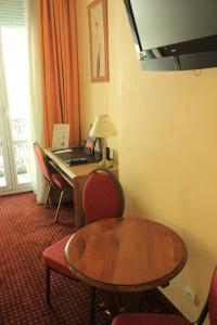 Zimmer mit einem Schreibtisch, einem Tisch und Stühlen in der Unterkunft Hôtel Foch in Lyon