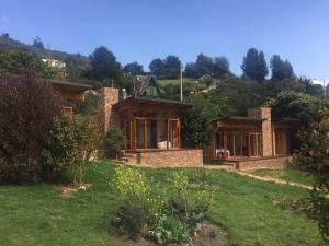 ein Haus auf einem Hügel mit einem grünen Hof in der Unterkunft Titué Refugio , Cabañas in La Calera