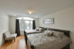 a bedroom with two beds and a chair and a window at New Blue Mountain Village Snowbridge Executive Townhome Sleeps 10 with Outdoor Pool and Shuttle in Nottawa +18 photos
