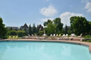 a large swimming pool with lounge chairs and tables at New Blue Mountain Village Snowbridge Executive Townhome Sleeps 10 with Outdoor Pool and Shuttle in Nottawa