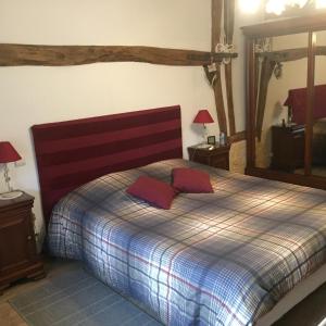 ein Schlafzimmer mit einem Bett mit roten Kissen darauf in der Unterkunft Le Chanois in Fontaine