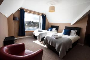 Habitación de hotel con 2 camas, silla y ventana en The Kirkmichael Hotel, en Kirkmichael