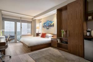 a bedroom with a bed and a large window at The Gotham Hotel in New York