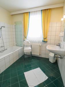 a bathroom with a tub and a sink and a toilet at Aparthotel Alpina in Filzmoos