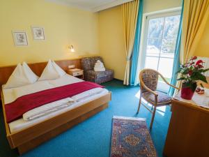 Pokój hotelowy z łóżkiem, krzesłem i oknem w obiekcie Aparthotel Alpina w mieście Filzmoos