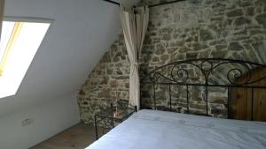 Ce lit se trouve dans un dortoir doté d'un mur en pierre. dans l'établissement Gite Rouge and la Ferme Blanche, à MÃ©nil-Vin