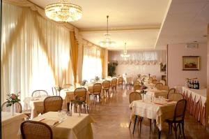 una sala da pranzo con tavoli e sedie bianchi di Hotel Torretta a Montecatini Terme