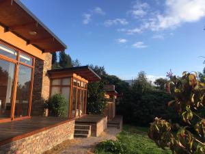 une maison avec une terrasse couverte et une terrasse dans l'établissement Titué Refugio , Cabañas, à La Calera