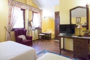 a bedroom with a bed and a television and a chair at Posada Carpe Diem in Liérganes