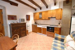 cocina con armarios de madera, mesa y sofá en Apartamentos Sorripas 1 hab en Bielsa