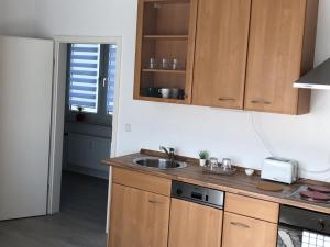 uma cozinha com armários de madeira e um lavatório em Helle Ferienwohnung an der Rheinpromenade 50 qm em Duisburg