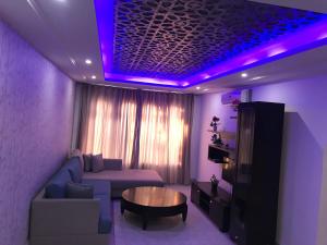 a living room with a couch and a table and purple lights at Appartement Touta écologique familial in Ḩawmat al Badawīyīn