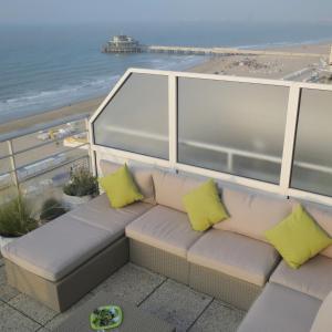 a couch with yellow pillows on a balcony with a beach at Penthouse SEAFLOWER in Blankenberge