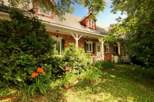 a brick house with flowers in the yard at Vieille Maison Rustique Espace Intéressant in Quebec City