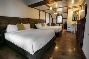 2 camas en una habitación con suelo de madera en Auberge Seigneurie des Monts, en Sainte-Anne-des-Monts