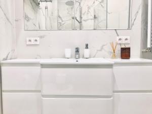 W białej łazience znajduje się umywalka i lustro. w obiekcie St. Florian Apartament w Warszawie