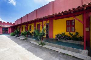 a red and yellow building with potted plants and flowers at Pousada dos Gravatais in Marataizes