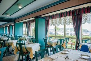 a dining room with tables and chairs and windows at Hotel las Dunas in Noja
