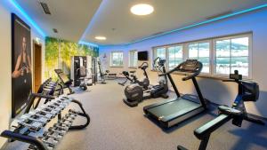 a gym with several treadmills and ellipticals in a room at Grizzly Sport & Motorrad Resort in Sankt Margarethen im Lungau