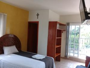 sypialnia z łóżkiem i krzyżem na ścianie w obiekcie DON CELES w mieście Paraíso