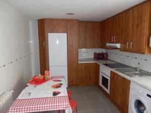 una pequeña cocina con armarios de madera y una mesa roja y blanca en SUNNSHINE, en Cuenca