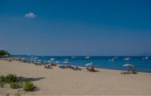 a group of people sitting on a beach with umbrellas at Vicky's Guesthouse in Kavos