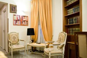 twee stoelen en een tafel in een kamer met boekenplanken bij B&B Lepanto in Messina