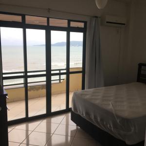 een slaapkamer met een bed en uitzicht op de oceaan bij Apartamento a Beira Mar in Meia Praia