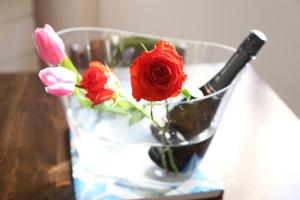 a glass vase with roses and a bottle on a table at Casa Mimi in Santa Flavia