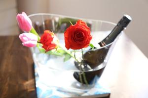 サンタ・フラーヴィアにあるCasa Mimiのガラスの花瓶(バラ付)とテーブルの上にボトル