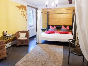 ein Schlafzimmer mit einem Bett mit roten Kissen und einem Stuhl in der Unterkunft Hotel Feldmaus in Olzheim