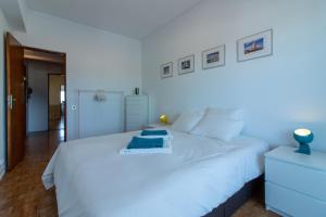 een slaapkamer met een wit bed met een blauw item erop bij Cacilhas Amazing view of Lisbon close to beach Caparica in Almada