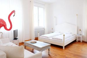 ein weißes Schlafzimmer mit einem Bett und einem Sofa in der Unterkunft Hotel Maurerhansl in Dießen am Ammersee