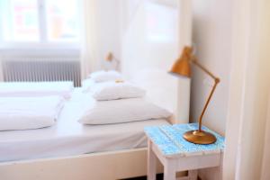 a bed with white sheets and a lamp on a table at Hotel Maurerhansl in Dießen am Ammersee