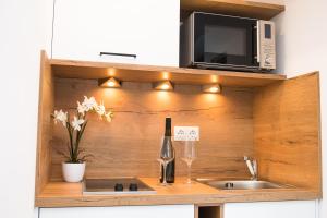 Your Home - City Apartment in Kufstein في كوفشتاين: مطبخ مع حوض وميكروويف وزجاجة من النبيذ