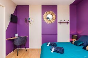 a bedroom with purple walls and a bed with a mirror at Appartement Le Paon in Toulouse