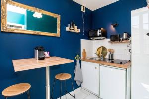 een keuken met blauwe muren en een aanrecht en krukken bij Appartement Le Paon in Toulouse